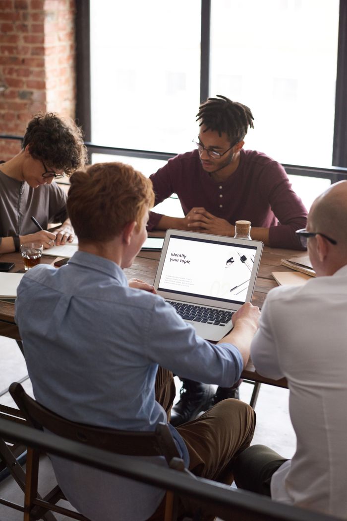 Four adults collaborate in a bright office for project research and brainstorming.